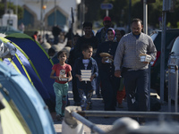 A family of migrants pictured in Kos harbour after they received a hot meals from local volunteers, as awaiting to be processed by the Greek...