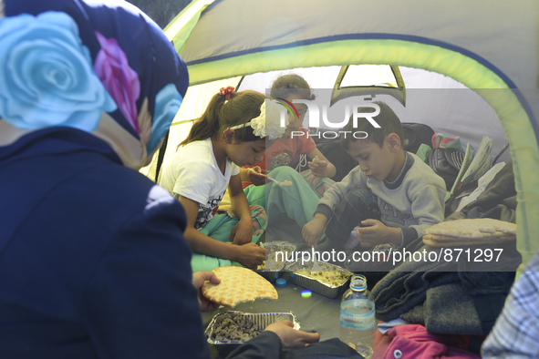 A family of migrants pictured in Kos harbour having a hot meals they received from local volunteers, as awaiting to be processed by the Gree...