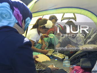 A family of migrants pictured in Kos harbour having a hot meals they received from local volunteers, as awaiting to be processed by the Gree...