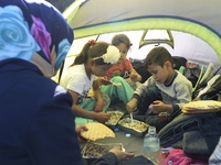 A family of migrants pictured in Kos harbour having a hot meals they received from local volunteers, as awaiting to be processed by the Gree...