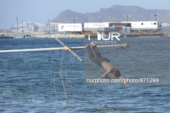 A migrant pictured jumping into sea in Kos harbour, as awaiting to be processed by the Greek police and given paperwork entitling them to le...