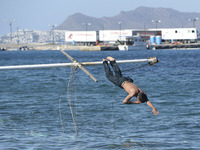 A migrant pictured jumping into sea in Kos harbour, as awaiting to be processed by the Greek police and given paperwork entitling them to le...