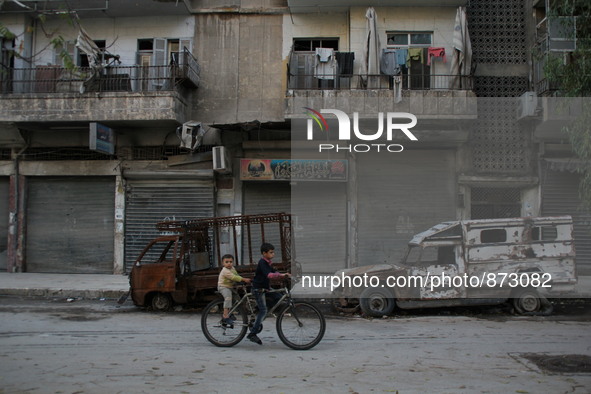 A Syrian boy rides a bicycle Beside the wreckage of a vehicle in a rebel-controlled area Bab al-hadid in the northern Syrian city of Aleppo...