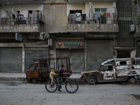 A Syrian boy rides a bicycle Beside the wreckage of a vehicle in a rebel-controlled area Bab al-hadid in the northern Syrian city of Aleppo...