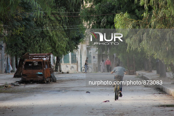 A Syrian boy rides a bicycle Beside the wreckage of a vehicle in a rebel-controlled area Bab al-hadid in the northern Syrian city of Aleppo...