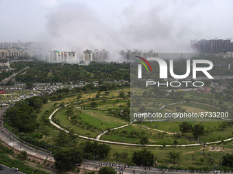 Nearby residential buildings are engulfed by dust as the Supertech Twin Towers collapse following a controlled demolition by explosion after...