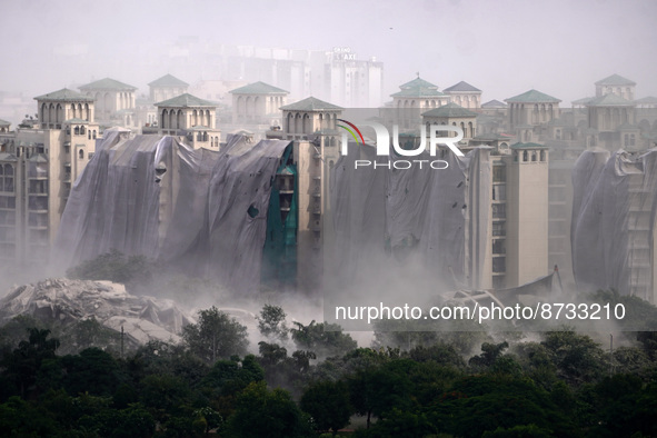 Nearby residential buildings are engulfed by dust as the Supertech Twin Towers collapse following a controlled demolition by explosion after...