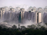 Nearby residential buildings are engulfed by dust as the Supertech Twin Towers collapse following a controlled demolition by explosion after...