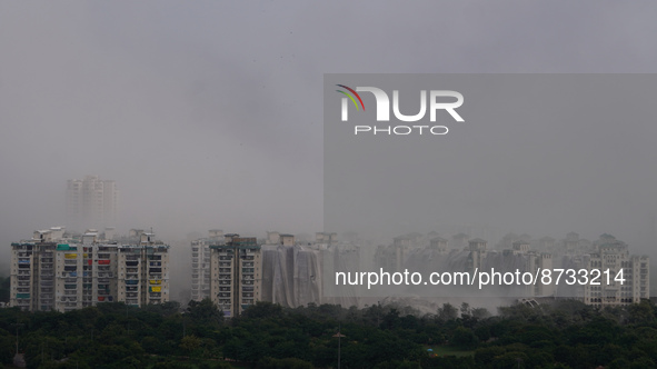 Nearby residential buildings are engulfed by dust as the Supertech Twin Towers collapse following a controlled demolition by explosion after...