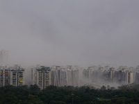 Nearby residential buildings are engulfed by dust as the Supertech Twin Towers collapse following a controlled demolition by explosion after...