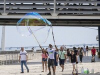 People are seen performing outdoor activities in the surroundings of the Tejo river promenade in Oriente. Lisbon, August 23, 2022. The manda...