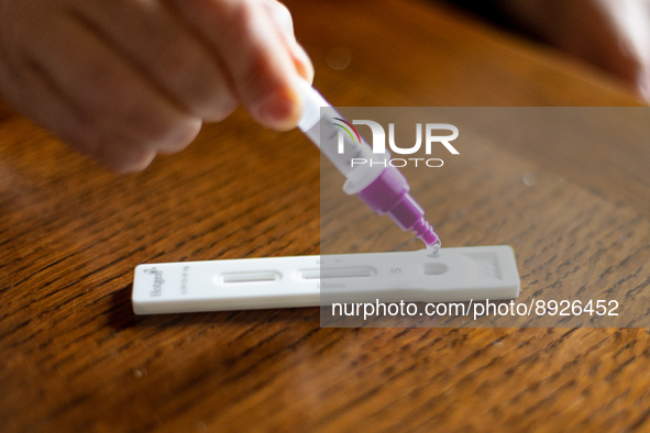 A woman drops a swab sample into an antigen test strip at home in L’Aquila, Italy, on September 29, 2022.  