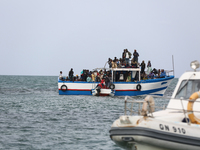 A small sailboat crowded with nearly 118 people and a unity of Tunisian guards coast watch them (