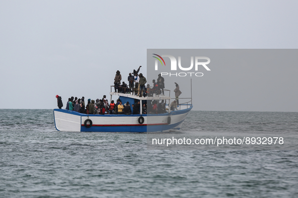 Migrants on small sailboat waiting to transfer  