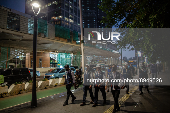 People wear protective face masks walk in business district on the main street in Jakarta on 3 October 2022. President Joko Widodo mentioned...