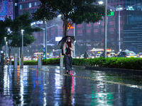 Women with umbrella wear protective face masks walk in business district on the main street in Jakarta on 3 October 2022. President Joko Wid...