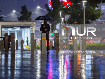 A man with umbrella wear protective face masks walk in business district on the main street in Jakarta on 3 October 2022. President Joko Wid...