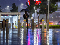 A man with umbrella wear protective face masks walk in business district on the main street in Jakarta on 3 October 2022. President Joko Wid...