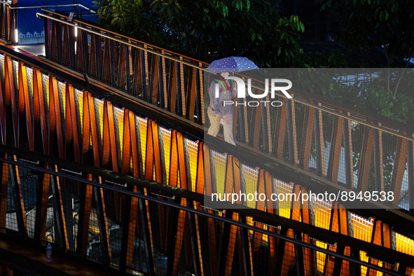 Women with umbrella wear protective face masks walk at pedestrian bridge in business district on the main street in Jakarta on 3 October 202...