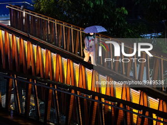 Women with umbrella wear protective face masks walk at pedestrian bridge in business district on the main street in Jakarta on 3 October 202...