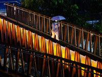 Women with umbrella wear protective face masks walk at pedestrian bridge in business district on the main street in Jakarta on 3 October 202...