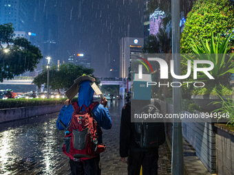 People cover their heads with boxes to avoid the rain  in business district, Jakarta on 3 October 2022. President Joko Widodo mentioned the...