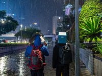 People cover their heads with boxes to avoid the rain  in business district, Jakarta on 3 October 2022. President Joko Widodo mentioned the...