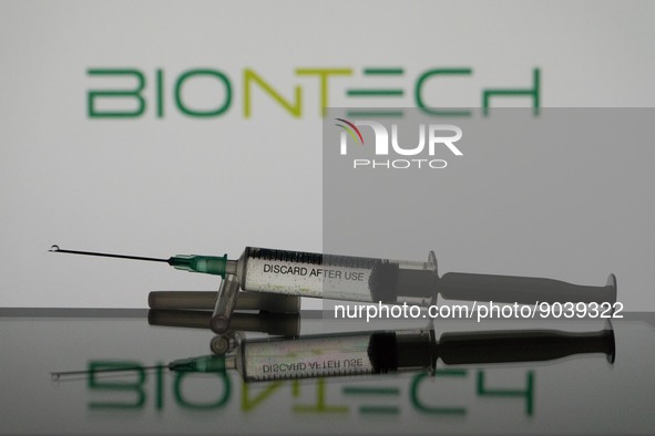 In this photo illustration a covid-19 vaccine is seen with the Biontech logo in the background. (Photo Illustration by Nikos Pekiaridis/NurP...