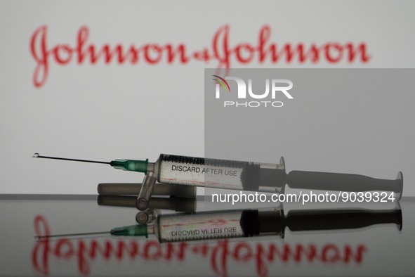 In this photo illustration a covid-19 vaccine is seen with the Johnson&Johnson logo in the background. (Photo Illustration by Nikos Pekiarid...