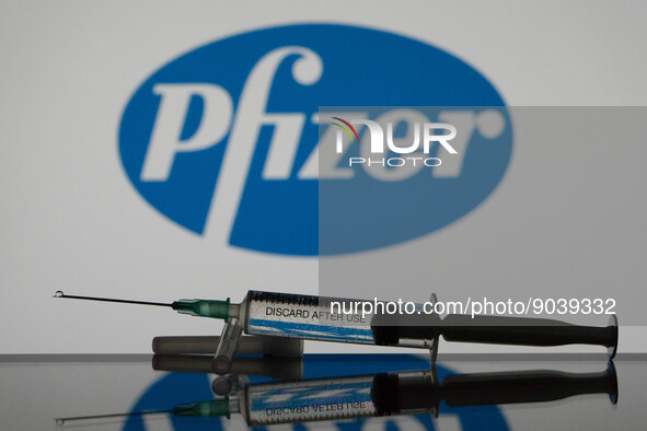 In this photo illustration a covid-19 vaccine is seen with the Pfizer logo in the background. (Photo Illustration by Nikos Pekiaridis/NurPho...