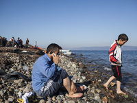 A man makes a call moments after refugees and migrants riding a dinghy reached the shores of the Greek island of Lesbos after crossing the A...