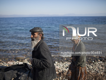 A couple of Afghans walk on a beach of Lesbos after refugees and migrants riding a dinghy reached the shores of the Greek island after cross...