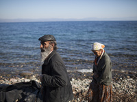 A couple of Afghans walk on a beach of Lesbos after refugees and migrants riding a dinghy reached the shores of the Greek island after cross...