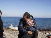 A man from Syria embraces his son as refugees and migrants riding a dinghy reach the shores of the Greek island of Lesbos after crossing the...