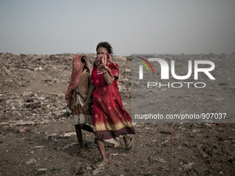 Children scavengers are hiding their faces. Dhapa, Kolkata, India. January 20, 2015. *** Go to http://nurphoto.com/en/reportages/51696 to se...