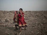 Children scavengers are hiding their faces. Dhapa, Kolkata, India. January 20, 2015. *** Go to http://nurphoto.com/en/reportages/51696 to se...