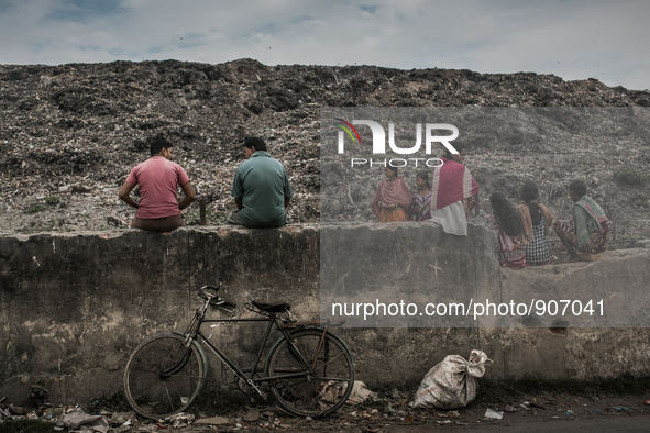 Local people and scavengers are sitting over the boundary wall of waste dumping ground. Dhapa, Kolkata, India. January 17, 2015. *** Go to h...