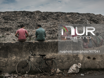 Local people and scavengers are sitting over the boundary wall of waste dumping ground. Dhapa, Kolkata, India. January 17, 2015. *** Go to h...