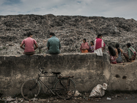 Local people and scavengers are sitting over the boundary wall of waste dumping ground. Dhapa, Kolkata, India. January 17, 2015. *** Go to h...