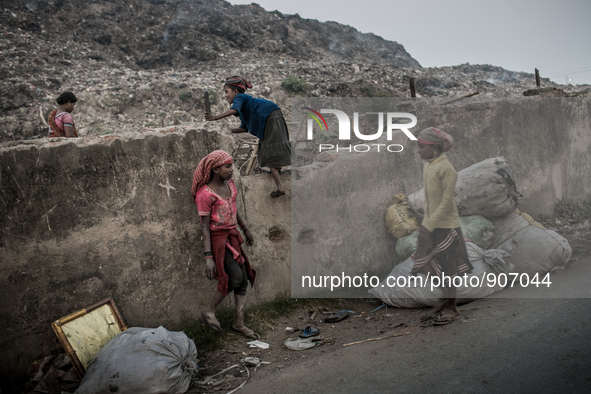 Children scavengers are passing over the boundary wall to go for waste picking in the waste mountain. Dhapa, Kolkata, India. January 20, 201...