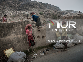 Children scavengers are passing over the boundary wall to go for waste picking in the waste mountain. Dhapa, Kolkata, India. January 20, 201...