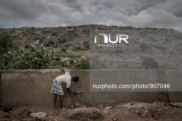 A man is building boundary wall to give the waste mountain a support as the waste overflows. Dhapa, Kolkata, India. September 12, 2015. ***...