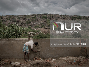 A man is building boundary wall to give the waste mountain a support as the waste overflows. Dhapa, Kolkata, India. September 12, 2015. ***...