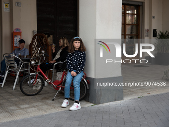 A young girl sitting on her bicycle at the café bar in the monumental Piazza della Repubblica, formerly Piazza della Rivoluzione, built in a...