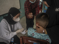 An officer injects a vaccine to a student on child immunization at SD Inpres Palupi, Palu City, Central Sulawesi Province, Indonesia on Octo...