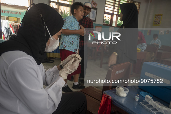 A health worker prepares a vaccine injection for a student on child immunization at SD Inpres Palupi, Palu City, Central Sulawesi Province,...