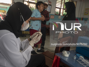 A health worker prepares a vaccine injection for a student on child immunization at SD Inpres Palupi, Palu City, Central Sulawesi Province,...