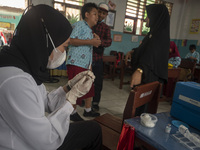 A health worker prepares a vaccine injection for a student on child immunization at SD Inpres Palupi, Palu City, Central Sulawesi Province,...