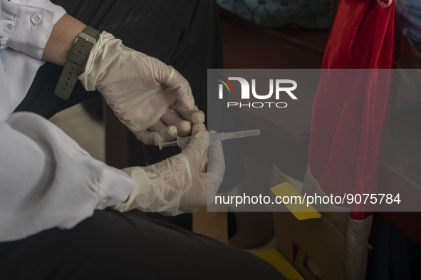 A health worker prepares a vaccine injection for a student on child immunization at SD Inpres Palupi, Palu City, Central Sulawesi Province,...