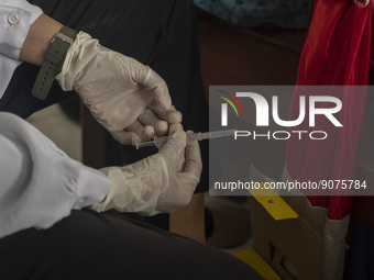 A health worker prepares a vaccine injection for a student on child immunization at SD Inpres Palupi, Palu City, Central Sulawesi Province,...